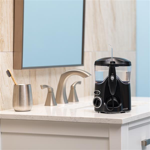 Black Ultra countertop water flosser on a bathroom sink.