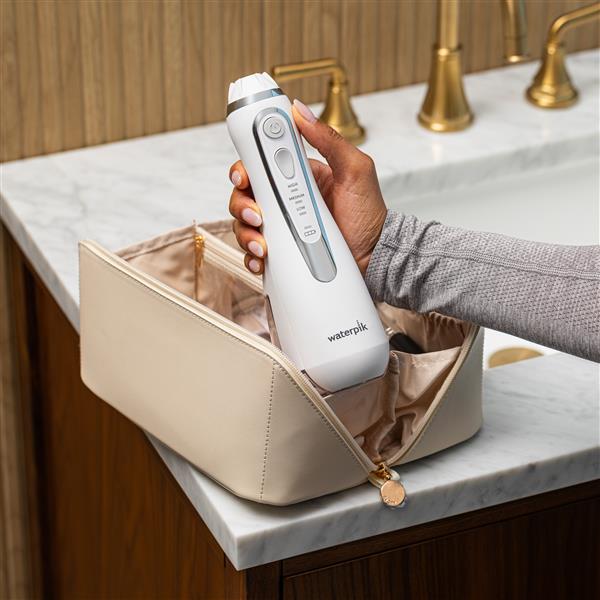 White Cordless Advanced 2.0 handheld water flosser, without tip, taken out of a toiletry bag.