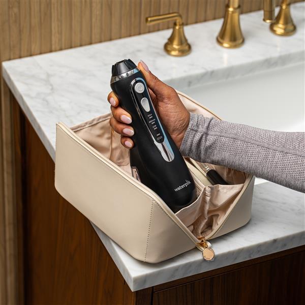 Black Cordless Advanced 2.0 handheld water flosser, without tip, taken out of a toiletry bag.