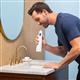 White Cordless 1000 handheld water flosser in use, with person leaning over the bathroom sink.