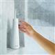 White Cordless Plus 5000 water flosser on a shower ledge, with a hand reaching for it.