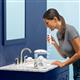 White Ultra countertop water flosser in use, with person leaning over the bathroom sink.