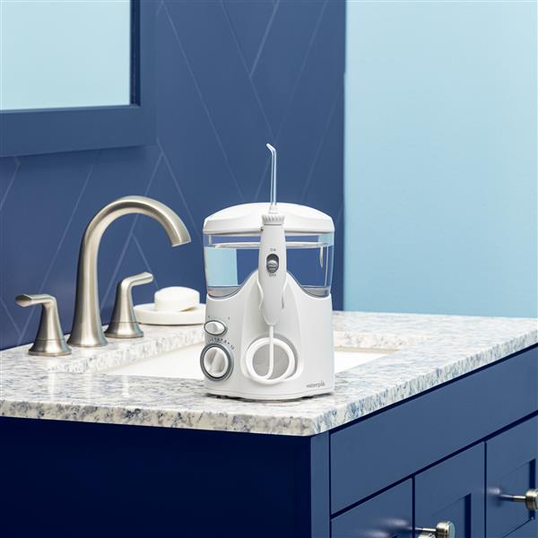 White Ultra countertop water flosser on a bathroom sink.