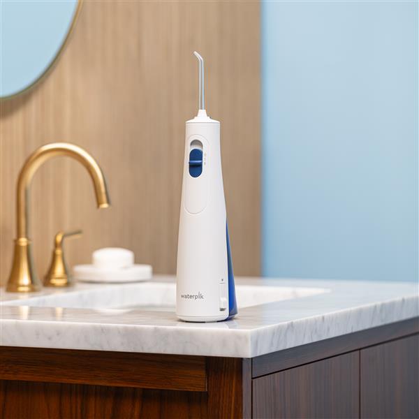 Hydropulseur portatif sans fil 1000 blanc sur un lavabo de salle de bain.