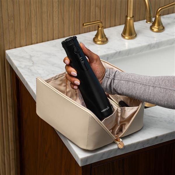 Hydropulseur portatif sans fil Plus 5000 noir, sans embout, sorti d’une trousse de toilette.
