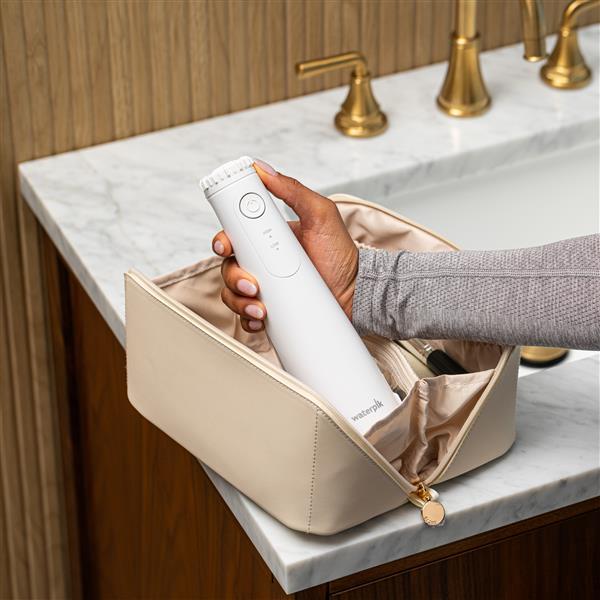 Hydropulseur portatif sans fil Plus 5000 blanc, sans embout, sorti d’une trousse de toilette.