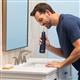 Hydropulseur portatif sans fil 1000 bleu en cours d’utilisation, une personne penchée au-dessus du lavabo de la salle de bain.