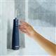 Hydropulseur sans fil 1000 bleu sur un rebord de douche, une main tendue vers l’appareil.