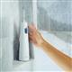 Hydropulseur sans fil 1000 blanc sur un rebord de douche, une main tendue vers l’appareil.