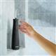 Hydropulseur sans fil Plus 5000 noir sur un rebord de douche, une main tendue vers l’appareil.