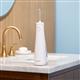 Hydropulseur portatif sans fil Plus 5000 blanc sur un lavabo de salle de bain.