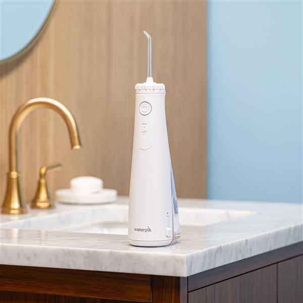 Hydropulseur portatif sans fil Plus 5000 blanc sur un lavabo de salle de bain.
